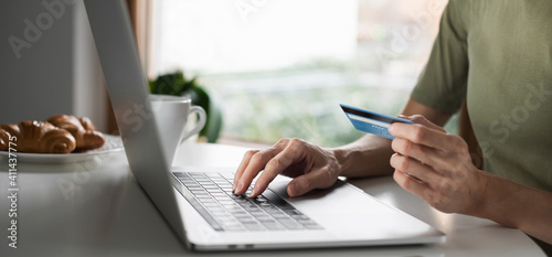 Woman hand holding credit card and using laptop computer at home panoramic banner, online shopping concept.