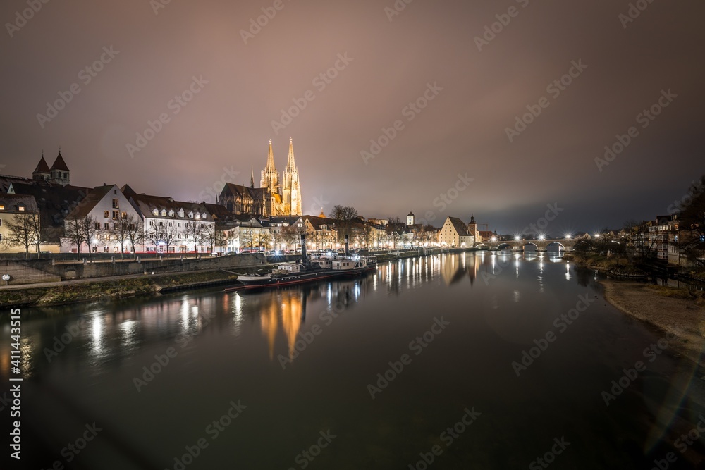 Blick zu der steinerne Brücke in Regensburg nachts im Nebel über den Fluss Donau mit dem beleuchteten Dom und historischer Altstadt , Deutschland