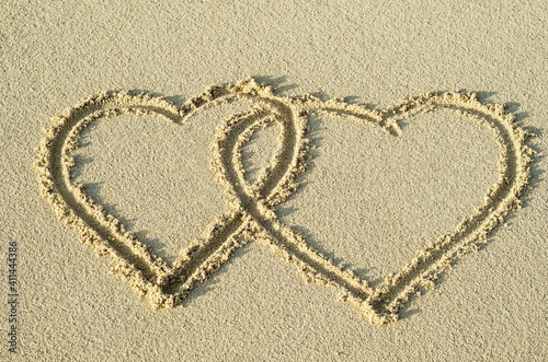 Konstfotografi Two entwined hearts drawn in the sand of a beach representing love, valentine, romance