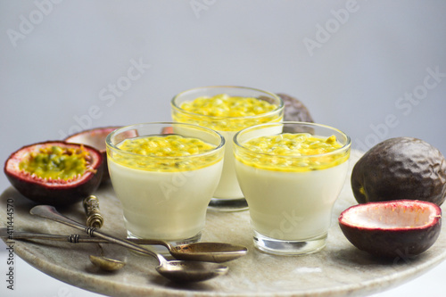 Italian dessert panna cotta in a glass cups with fresh passion fruits on a cake stand.
