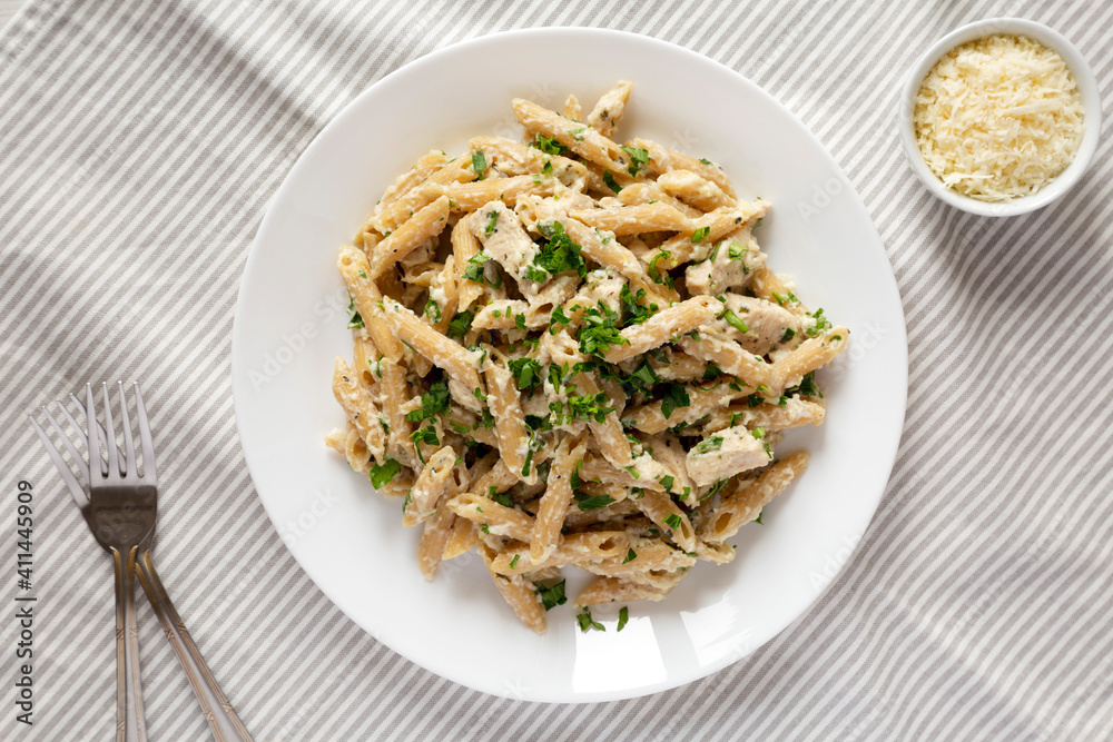 Homemade Chicken Alfredo Penne with Parsley on cloth, top view. Overhead, from above, flat lay.