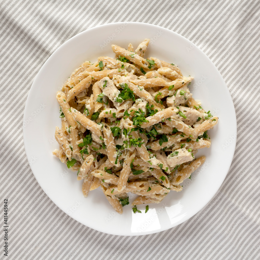 Homemade Chicken Alfredo Penne with Parsley on a white plate, top view. Overhead, from above, flat lay. Homemade Chicken Alfredo Penne with Parsley on a white plate, top view. Overhead, from above, flat lay.