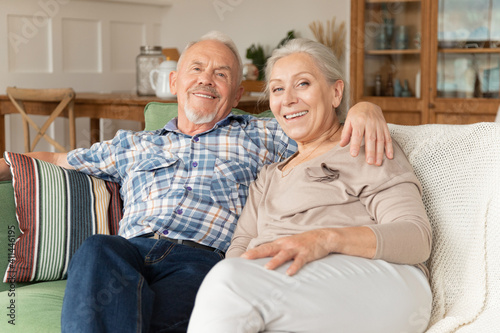 Elderly husband and wife relax on couch having fun laughing together. Happy senior couple rest on sofa at home, smile and enjoy leisure. Family romantic weekend at home, mature love concept