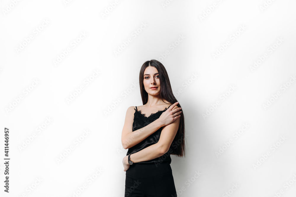 A young woman beautiful in black clothes sitting on a black chair on a white background isolated A young woman beautiful in black clothes sitting on a black chair on a white background isolated