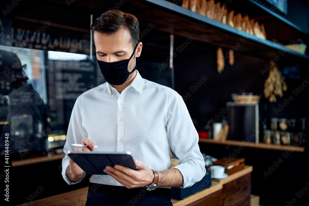 Waiter restaurant owner wearing mask using digital tablet - obrazy, fototapety, plakaty 