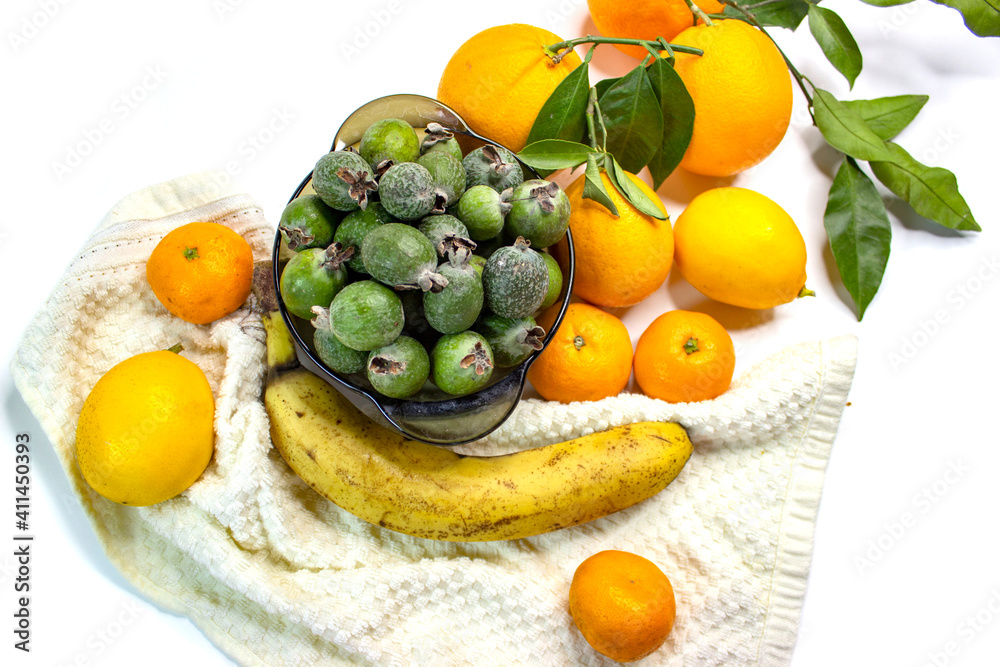 Ripe citrus fruits. Bright fresh fruit composition with foxes on a napkin. Orange, lemon, tangerine, feijoa, banana. Orange, yellow, green colors. Food market.