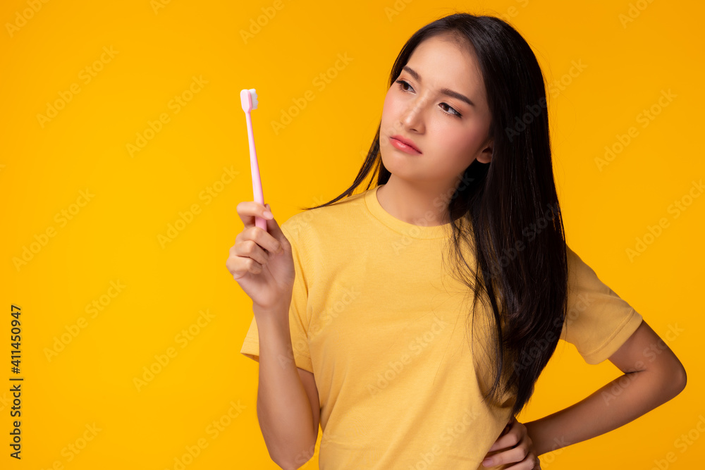 Unhappy young woman look at toothbrush, get unsatisfied it Attractive beautiful girl can’t choose good quality of toothbrush Pretty lady get confused and curious Dental care concept Yellow background Unhappy young woman look at toothbrush, get unsatisfied it Attractive beautiful girl can’t choose good quality of toothbrush Pretty lady get confused and curious Dental care concept Yellow background
