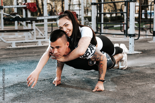 athletic young couple man and girl doing weight training together on the outdoor