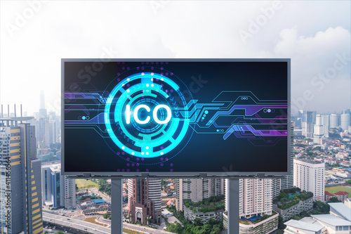 ICO hologram icon on billboard over panorama city view of Kuala Lumpur at day time. KL is the hub of blockchain projects in Malaysia, Asia. The concept of initial coin offering, decentralized finance