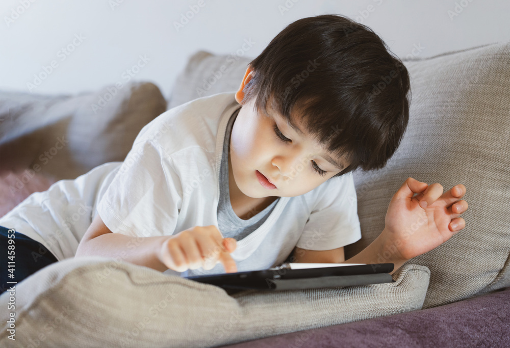 High key portrait Kid stay at home relaxing in living room in summer,Happy Child boy lying on sofa watching cartoon or playing game in retro filter,Homeschooling,E-learning online education High key portrait Kid stay at home relaxing in living room in summer,Happy Child boy lying on sofa watching cartoon or playing game in retro filter,Homeschooling,E-learning online education