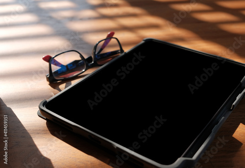 tablet mock up with eyeglasses on wooden table,morning
