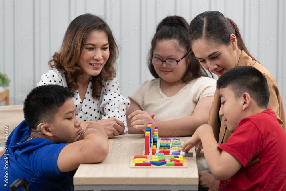 Group of special students in classroom, a down syndrome girl, two handicapped boys and cute Asian teacher playing toy and game together Group of special students in classroom, a down syndrome girl, two handicapped boys and cute Asian teacher playing toy and game together