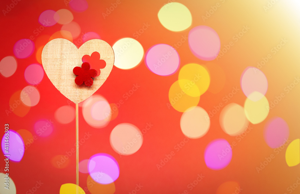 Wooden decorative heart on a stick. Space for text on the right. Red background with bokeh. Valentine's day and love concept. Sunbeams in the right corner. Wooden decorative heart on a stick. Space for text on the right. Red background with bokeh. Valentine's day and love concept. Sunbeams in the right corner.