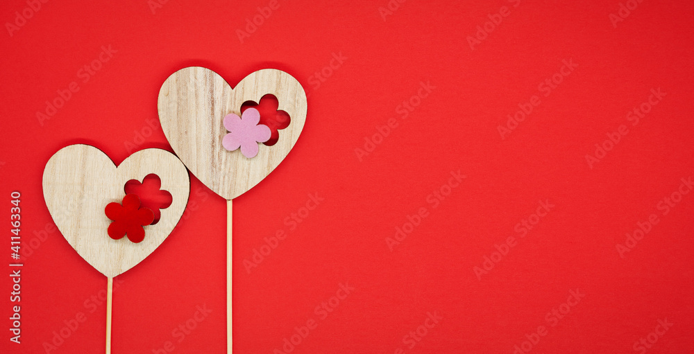 Festive background. Concept for valentine's day, love, wedding. Red background. Two decorative wooden hearts on sticks. Free space for text on the right.
