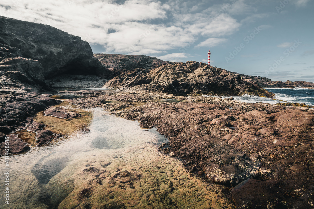 .lighthouse on the thing with a rocky landscape with a very calm natural pool