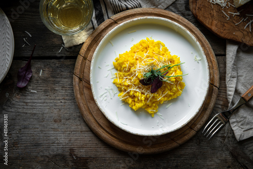 Rustic dinner with risotto all Milanese. Risotto with Saffron and parmesan on white plate on wooden table. 