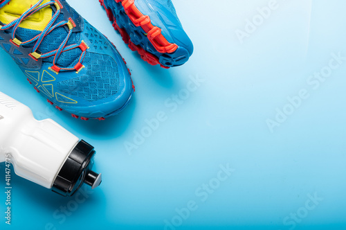Running shoes and a water bottle. Turquoise background and turquoise sneakers. Top. © vzwer