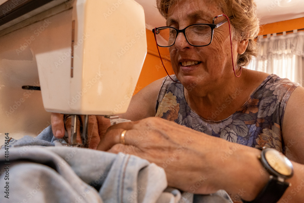 Obraz premium La abuela cosiendo con maquina de cocer la ropa de sus nietos 