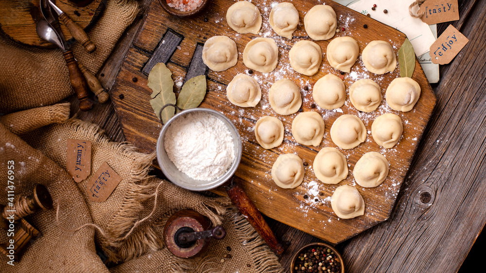 homemade dumplings with meat on rustic wooden board and table with flour, sackcloth homemade dumplings with meat on rustic wooden board and table with flour, sackcloth