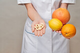 nutritionist doctor healthy lifestyle concept - holding fresh organic citrus fruits - grapefruit, orange, lemon and vitamin capsules