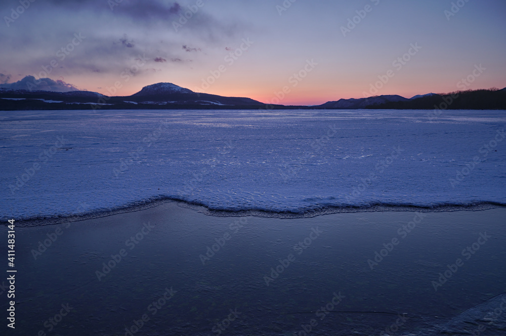 氷に覆われた冬の湖の夜明け。日本の北海道の屈斜路湖。
