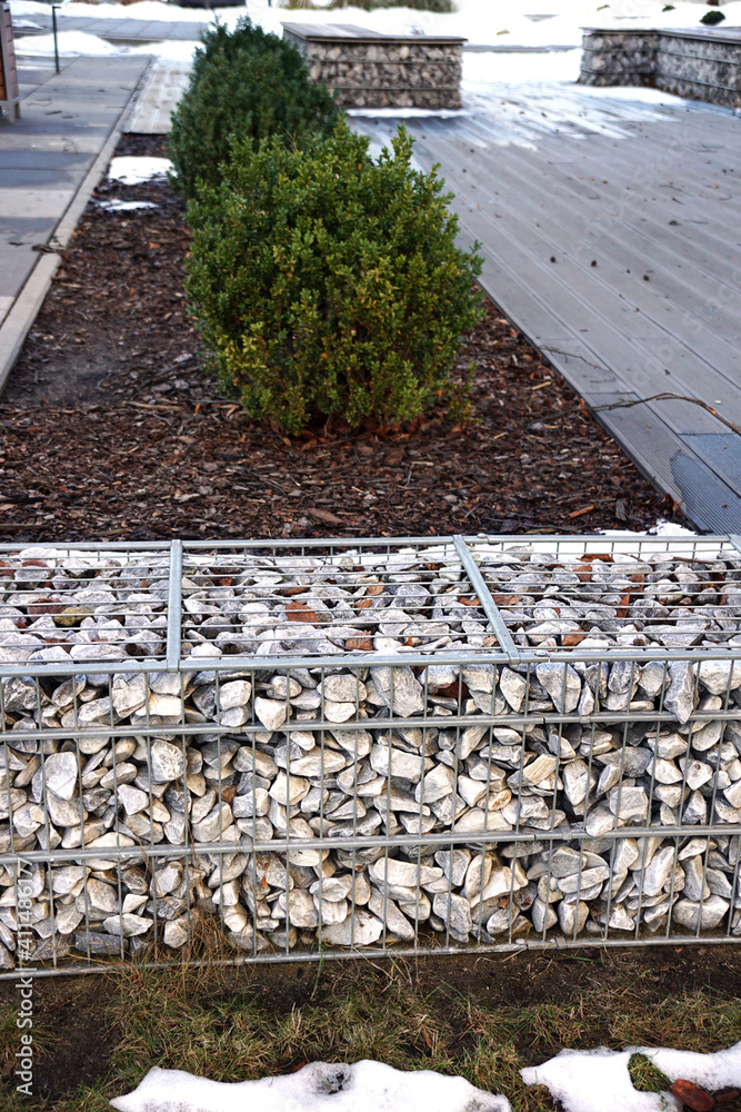 Obraz premium A fragment of space arrangement with the use of gabions. Separation of the street from the park area. Winter.