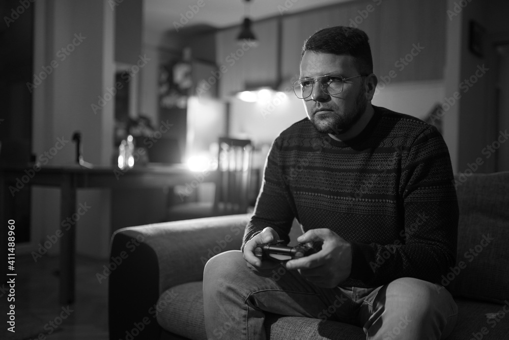 Young man sitting in living room and playing video games
