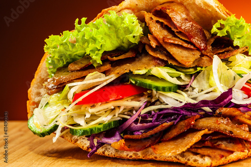 Kebab - grilled meat, bread and vegetables against orange gradient background