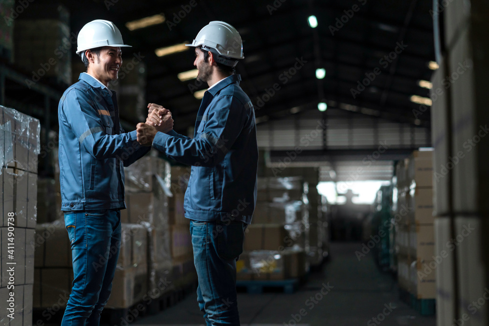 successful engineer teamwork casual positive converation working together in warehouse factory.Male worker with safety helmet checking quantity quality of product boxes on storage shelf in warehouse successful engineer teamwork casual positive converation working together in warehouse factory.Male worker with safety helmet checking quantity quality of product boxes on storage shelf in warehouse