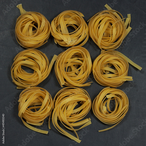 several servings of raw rolled noodles lie on a black table, background