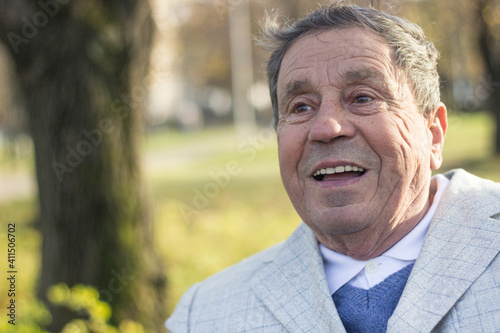Portrait of happy senior man smiling, in the public park, outdoors