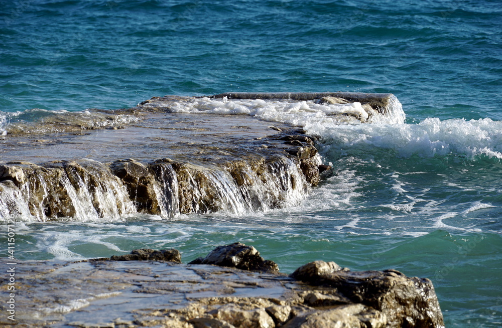 Wavy seawater overflowing over a stone reef