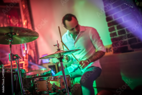 Drummer playing on drum set on stage.