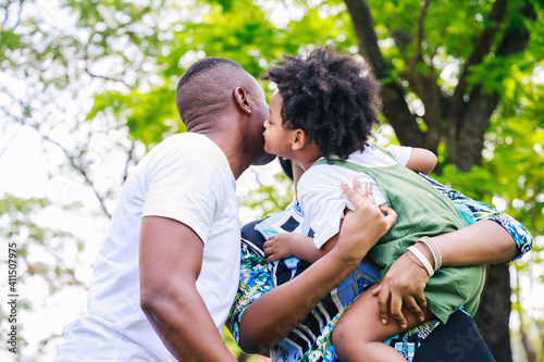 African American father and mother carrying his son and kisses on the cheek together with cheerful loving. Happy family.