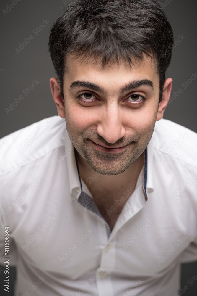 Portrait of caucasian man with brown eyes expressing positive emotions in studio, with grey background Portrait of caucasian man with brown eyes expressing positive emotions in studio, with grey background
