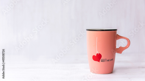 Valentine Day with pink cup coffee red heart on the cup, wood white background. Valentine Concept.