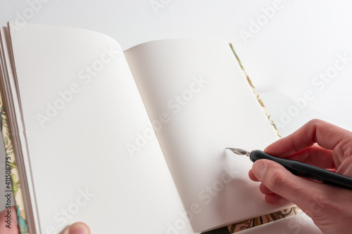 Bonita libreta para escribir poesía sobre fondo blanco y una pluma metalica con tinta china Espacio en blanco para texto photo