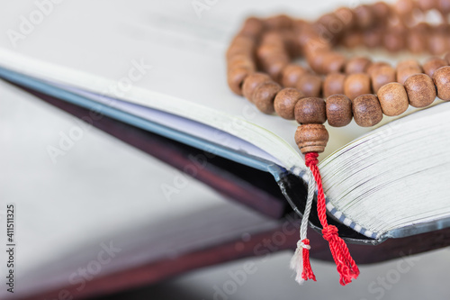 Rosary with red and white rope on wooden and Quran for prayer bead 