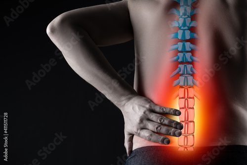 Pain in the spine, man with backache on black background, intervertebral hernia or disc injury concept photo