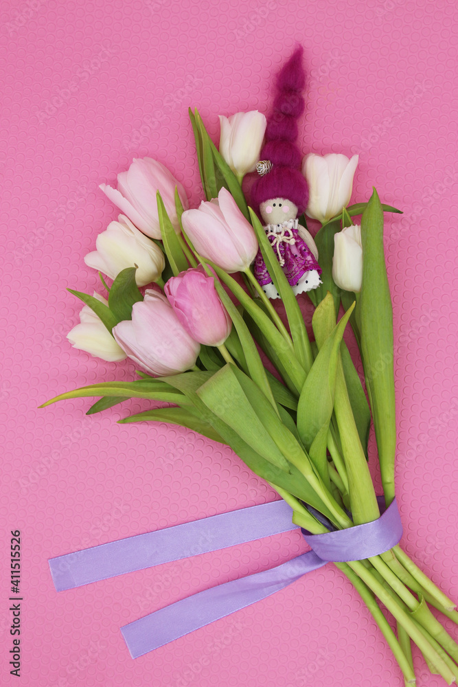 Bouquet of pink and white tulips with small purple doll on the pink background. 