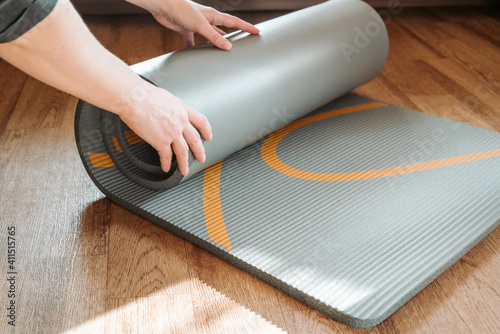 Woman rolls out yoga mat on the floor. Home fitness, sport, acttive lifestyle concept photo