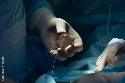 Surgeon holds a silicon implant of a testicle in his hand during the surgery close-up