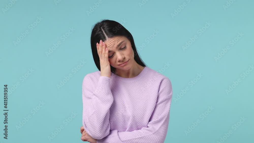 Tired young latin woman in violet sweater posing isolated on blue background studio. People lifestyle concept. Did not get enough sleep last night after party and barely got up in the morning yawning Tired young latin woman in violet sweater posing isolated on blue background studio. People lifestyle concept. Did not get enough sleep last night after party and barely got up in the morning yawning