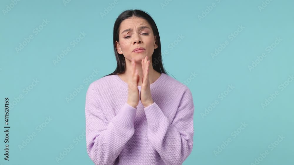 Pleading young latin woman 20s in violet sweater posing isolated on blue background studio. People lifestyle concept. Hold hands folded in prayer gesture keep fingers crossed begging about something Pleading young latin woman 20s in violet sweater posing isolated on blue background studio. People lifestyle concept. Hold hands folded in prayer gesture keep fingers crossed begging about something