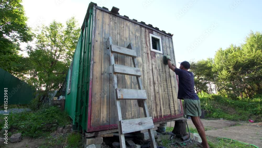 Timelapse of a man in cap polishing the wall planks of a cabin with a grinding machine Timelapse of a man in cap polishing the wall planks of a cabin with a grinding machine