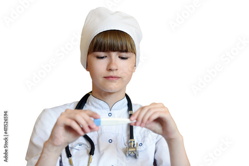 A young doctor girl with a stethoscope in a medical gown, looks at a thermometer, measures the temperature, insulation on a white background.