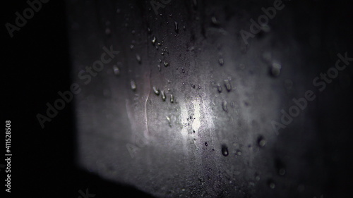 Misted car window with water drops at night