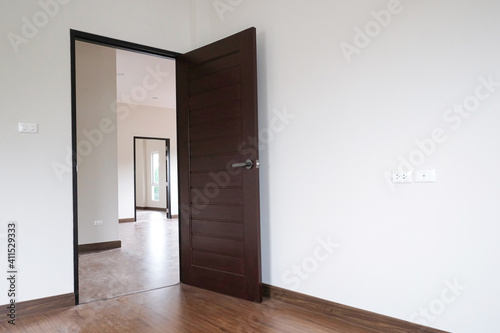 three room open brown door with white wall in new house. wooden laminate floor in bed room.