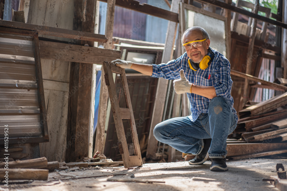 Asian senior carpenter show thumbs up old window frames for renovating at the carpentry workshop