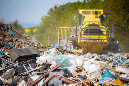 Close up of a bulldozer on the huge household landfill or dump waste, environmental or ecology problem